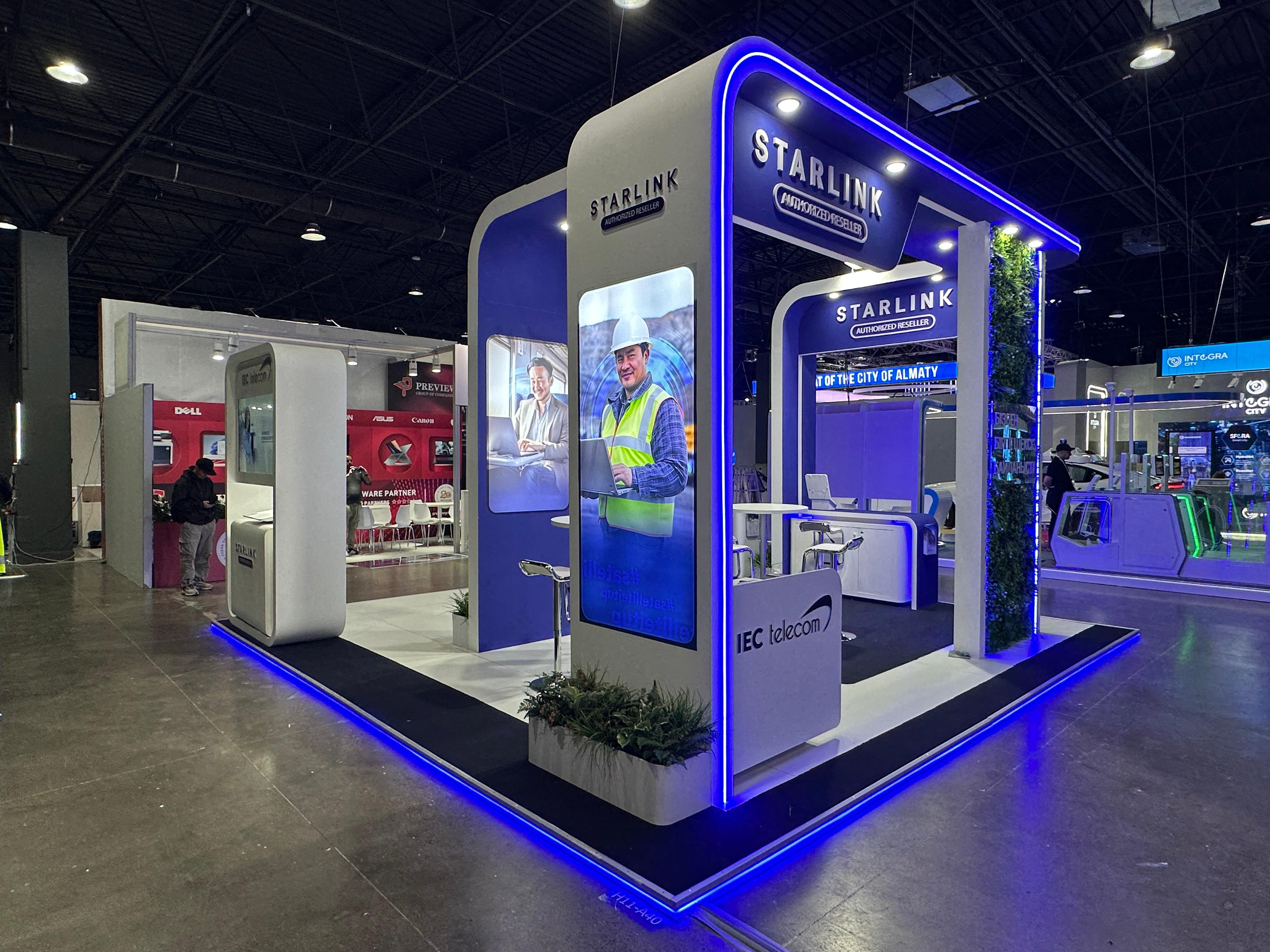 IEC Telecom stand at GITEX AI Kazakhstan 2026 — 3/4 angle showing Starlink Authorized Reseller arches, product showcase points and meeting space