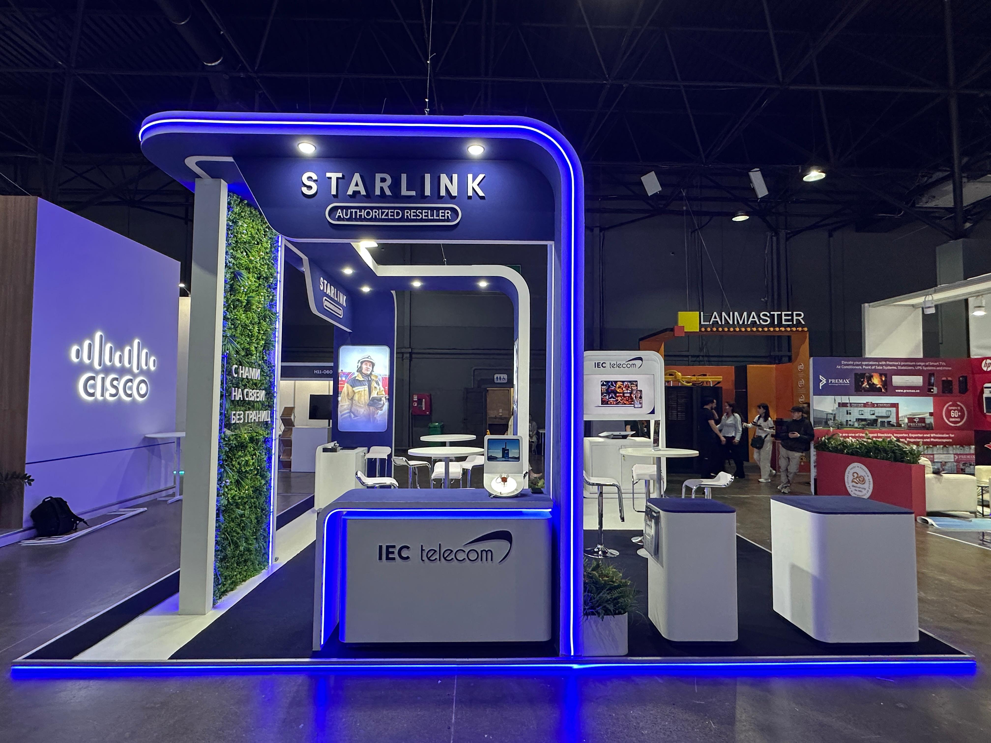 Russian-language branded environment on the IEC Telecom stand at GITEX AI Kazakhstan 2026 with Starlink Authorized Reseller signage and a living green wall